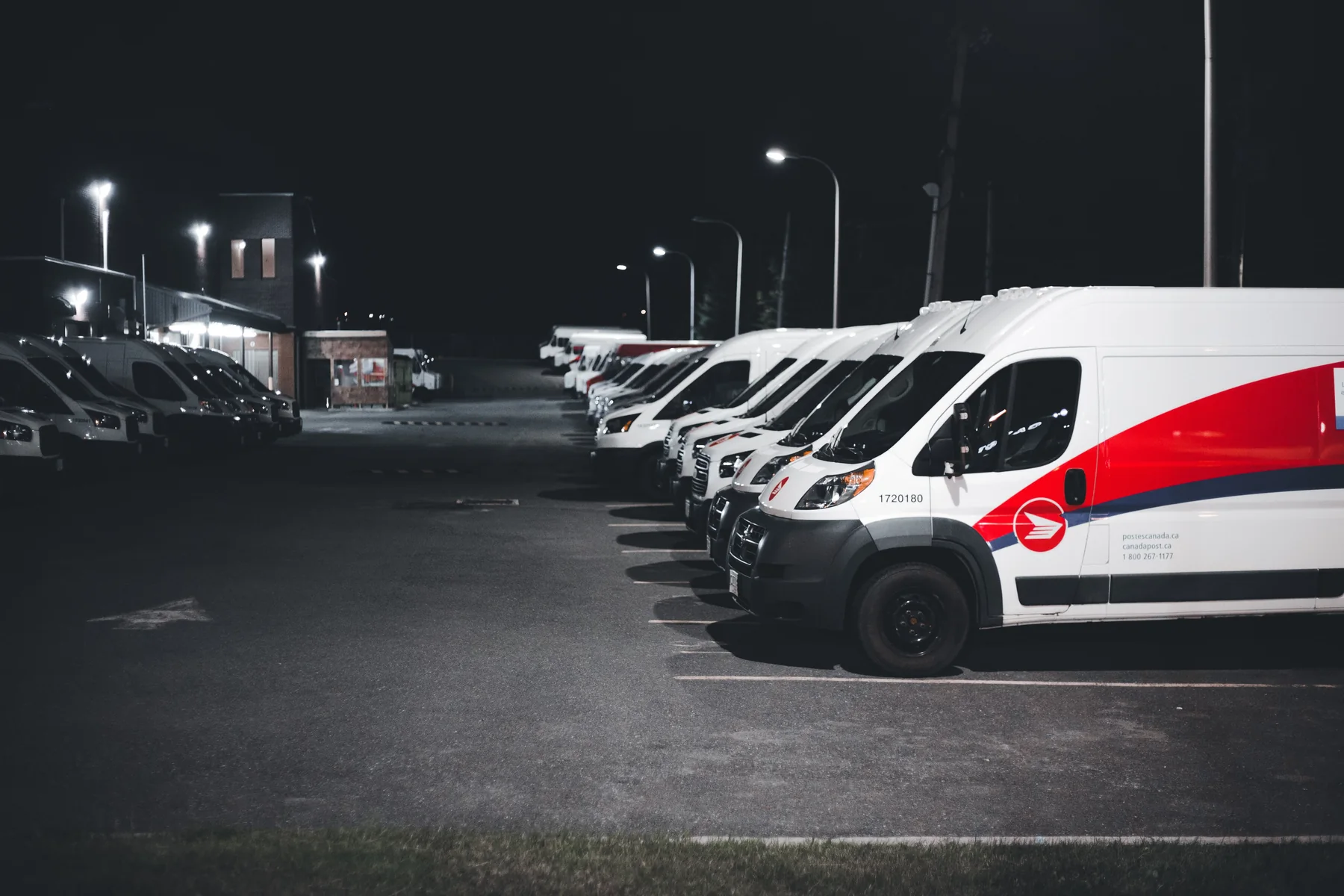 Verschillende bedrijfsvoertuigen op een parkeerterrein bij avondlicht