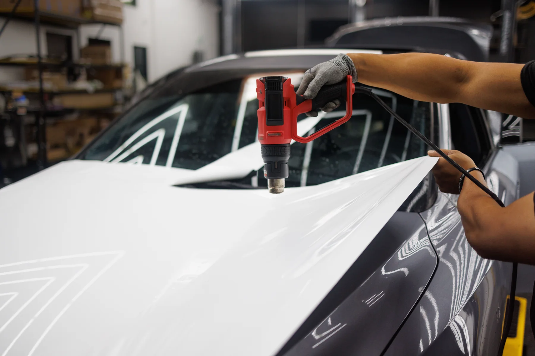 Technicus verwarmt witte wrapfolie met een heteluchtpistool